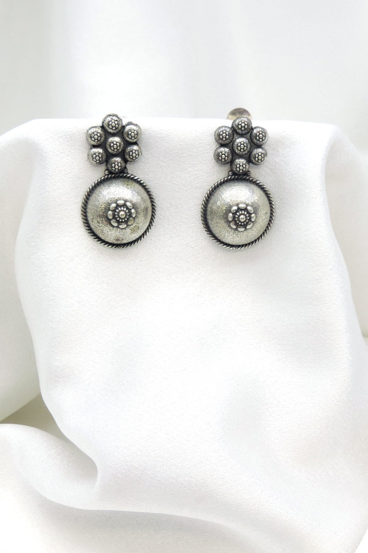 Oxidized silver floral circle drop earrings with intricate dotted detailing by joyrias