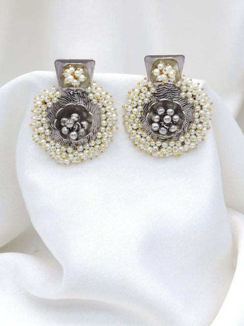 Oxidized dual-tone floral pearl stud earrings with intricate silver detailing by joyrias