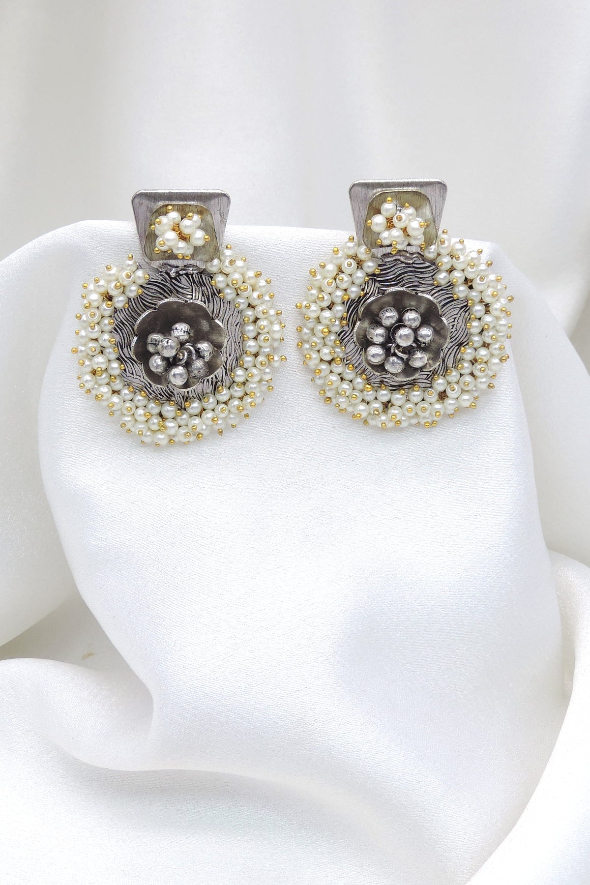 Oxidized dual-tone floral pearl stud earrings with intricate silver detailing by joyrias