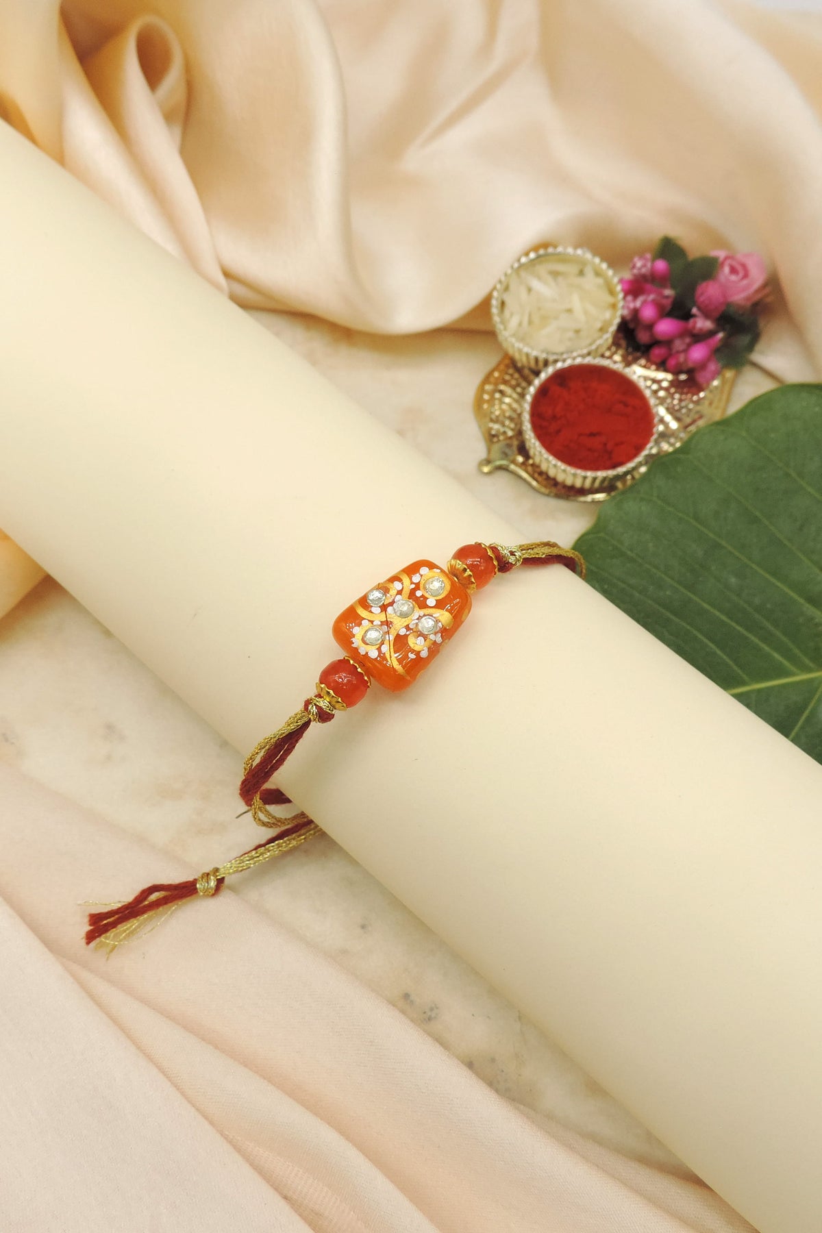 Handcrafted Orange Bead Rakhi with Crystal Floral Design
