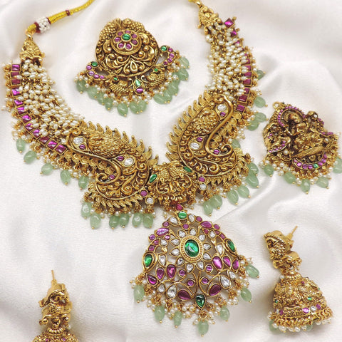 Temple gold-toned peacock Lakshmi kundan necklace set with matching earrings, maang tikka and pearl detailing by joyrias