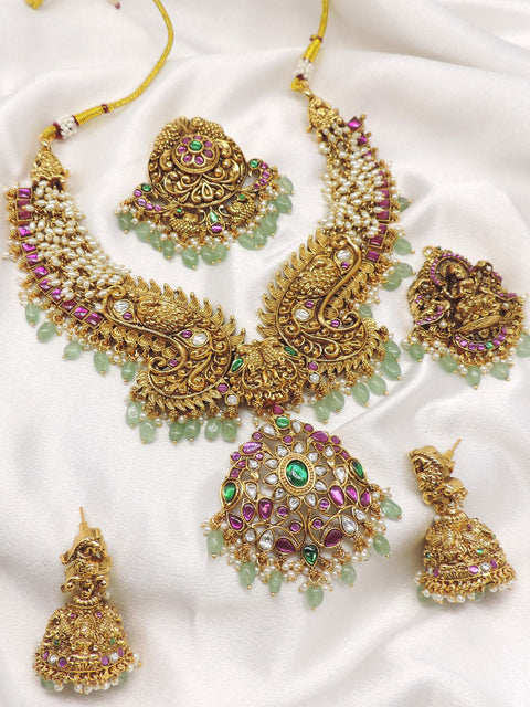 Temple gold-toned peacock Lakshmi kundan necklace set with matching earrings, maang tikka and pearl detailing by joyrias