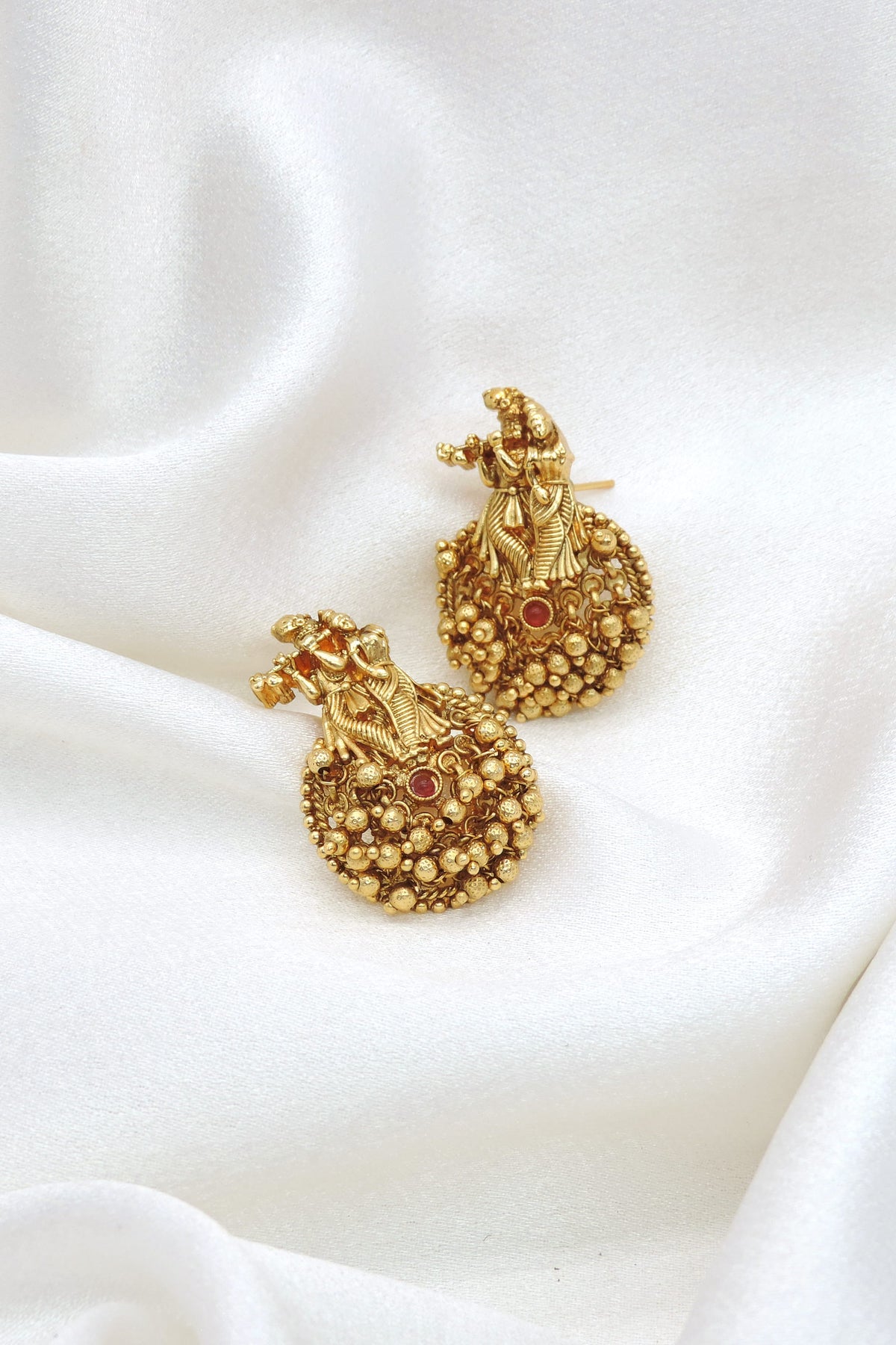 Gold-toned temple jhumka earrings with intricate traditional detailing by joyrias