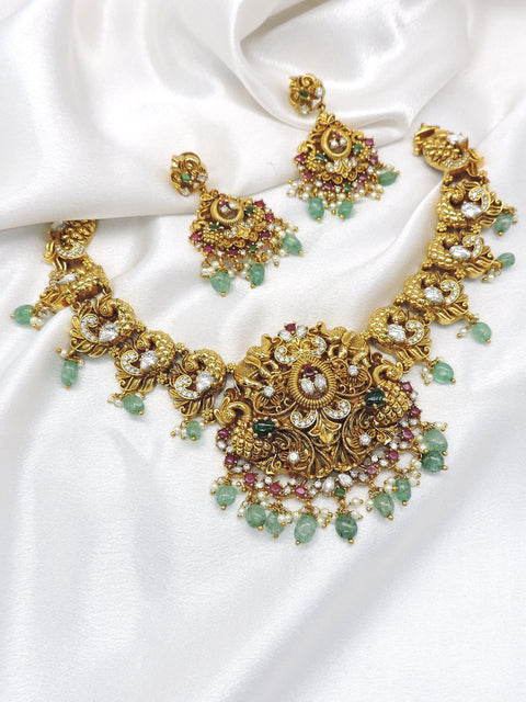 Heritage kundan polki temple necklace set with green stones, pearl detailing and matching earrings by joyrias