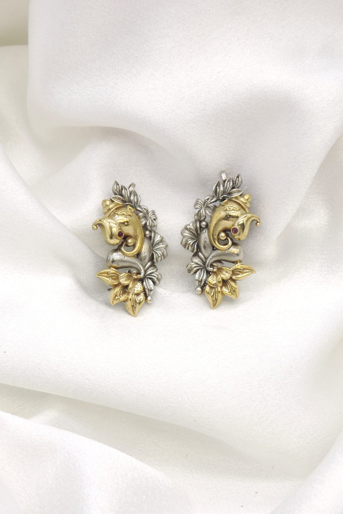 Oxidized dual-tone Ganesha cuff earrings with gold-toned and silver floral detailing by joyrias