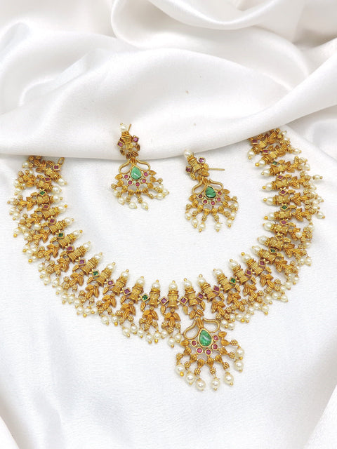 Gold-toned South Indian Guttapusalu style temple necklace set with green stones and pearl detailing by joyrias