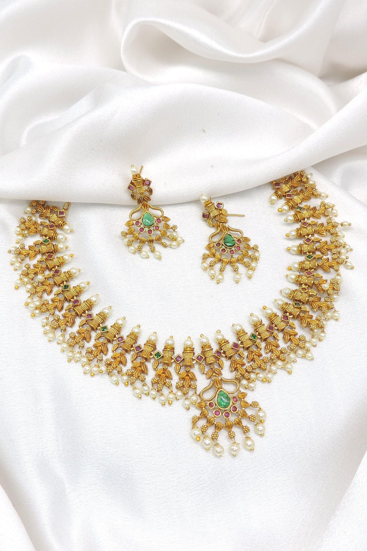 Gold-toned South Indian Guttapusalu style temple necklace set with green stones and pearl detailing by joyrias