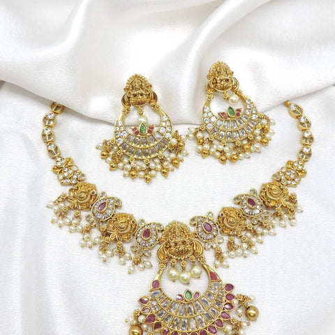 Gold-toned Lakshmi kundan temple necklace set with red green stones, pearl detailing and matching earrings by joyrias