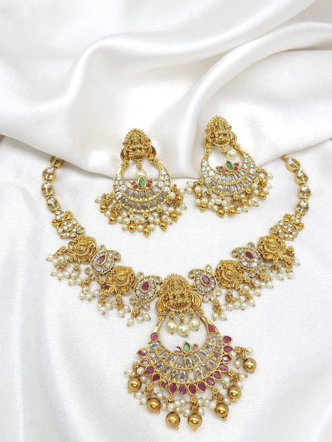 Gold-toned Lakshmi kundan temple necklace set with red green stones, pearl detailing and matching earrings by joyrias