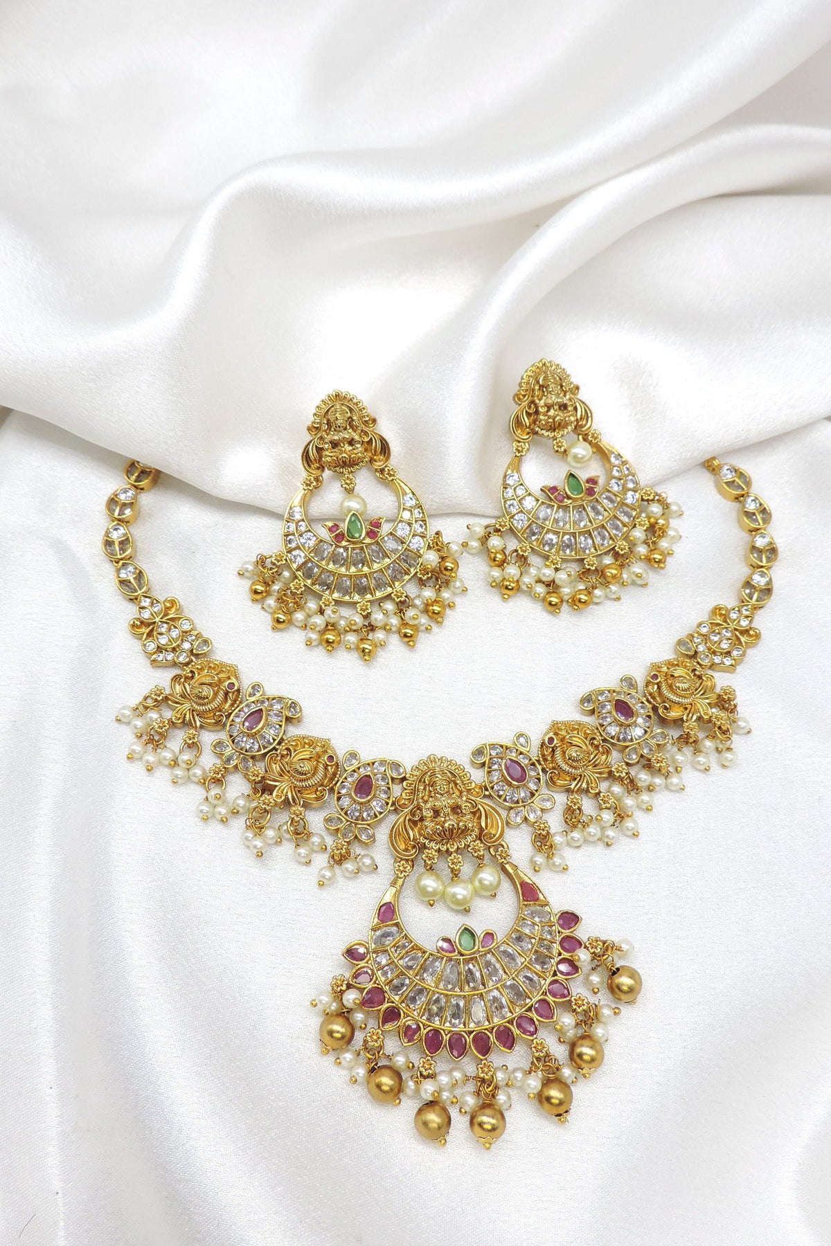 Gold-toned Lakshmi kundan temple necklace set with red green stones, pearl detailing and matching earrings by joyrias