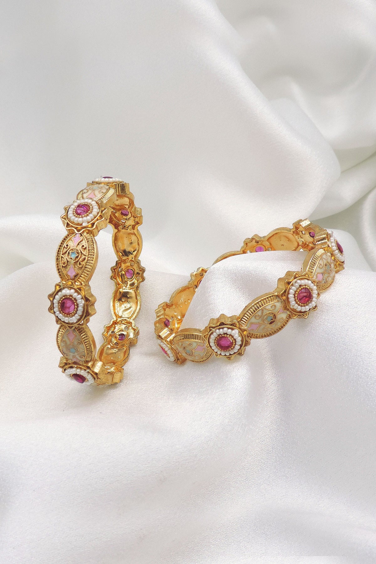 Gold-toned pink stone AD pearl bangle set with intricate floral detailing by joyrias