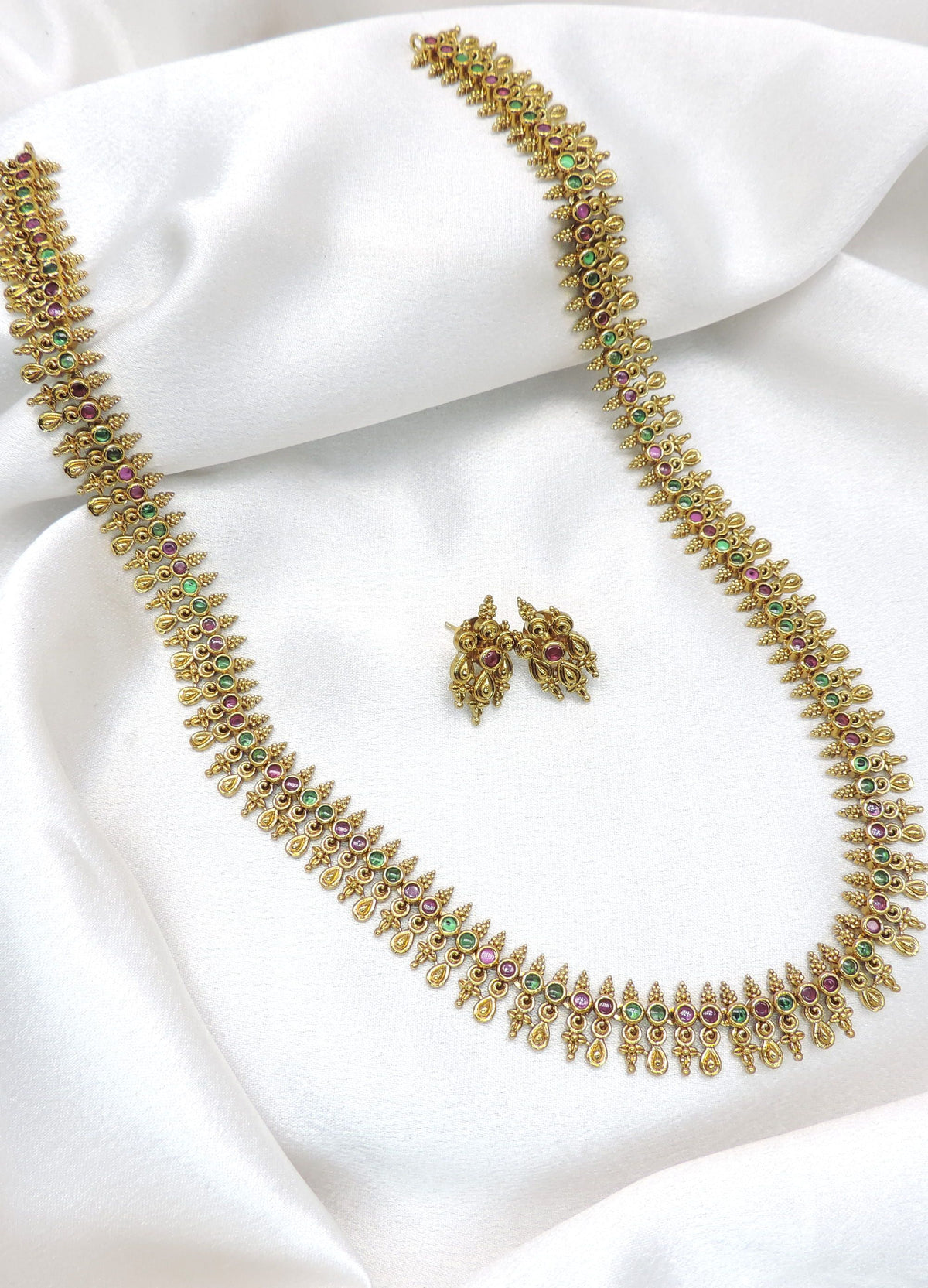 Classic long heritage temple necklace set with ruby and green stone detailing and matching earrings by joyrias