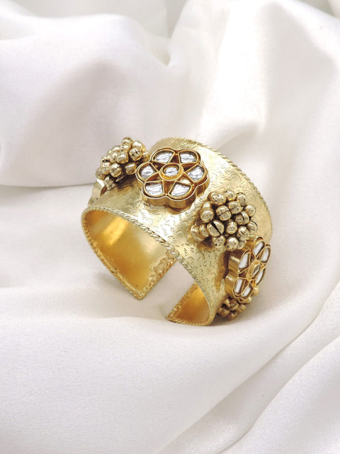 Gold-toned floral Kundan pearl cuff bracelet with intricate engraved detailing and traditional bead accents by joyrias