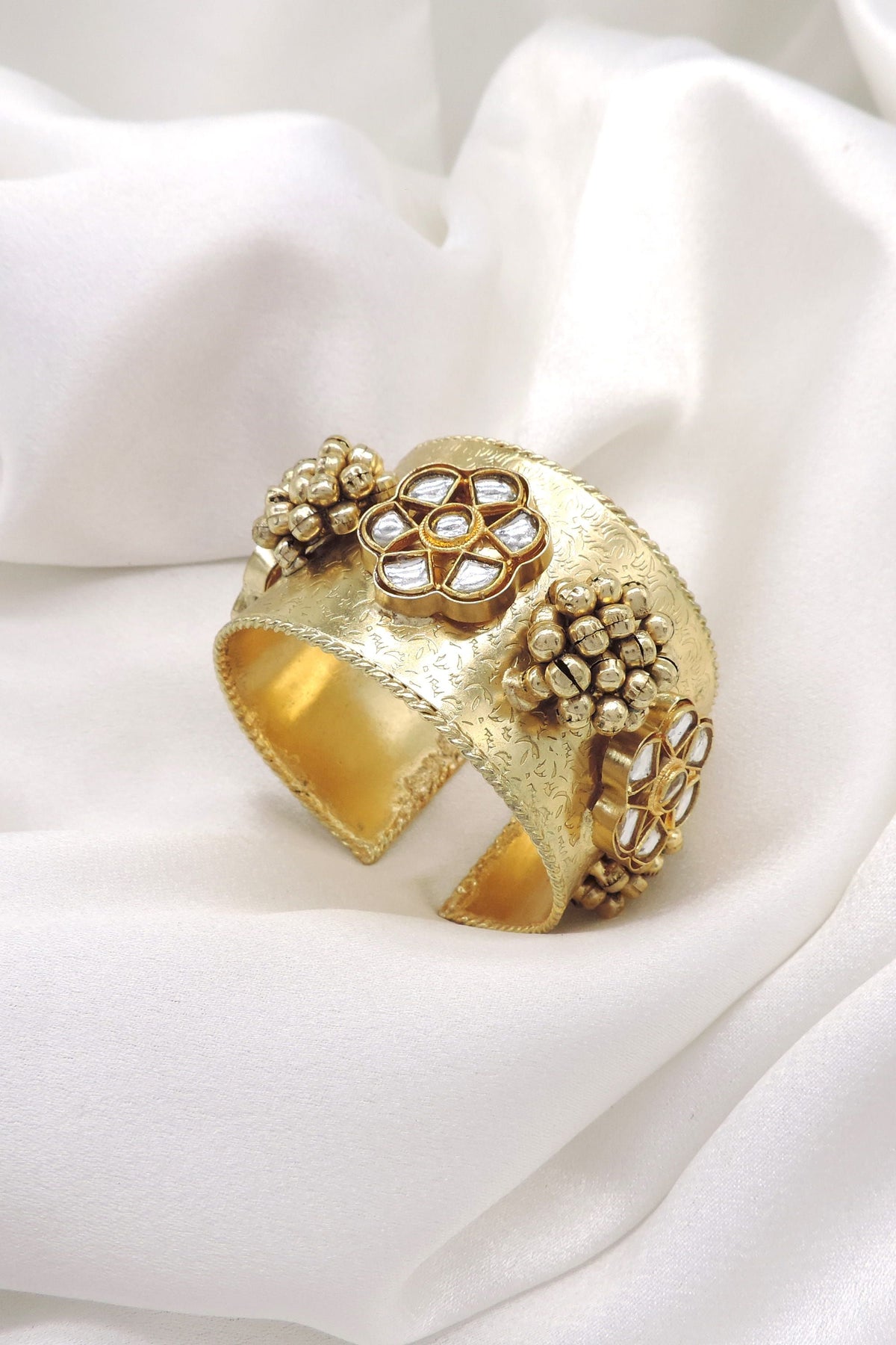 Gold-toned floral Kundan pearl cuff bracelet with intricate engraved detailing and traditional bead accents by joyrias