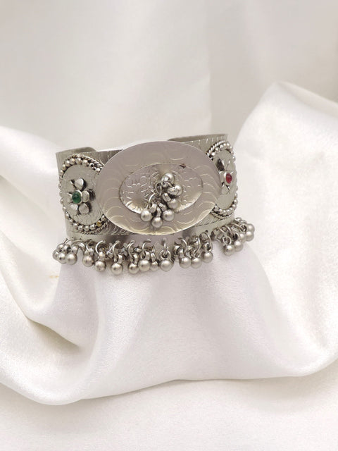 Oxidized silver floral ghungroo cuff bracelet with engraved detailing, colorful stone accents, and dangling silver charms by joyrias