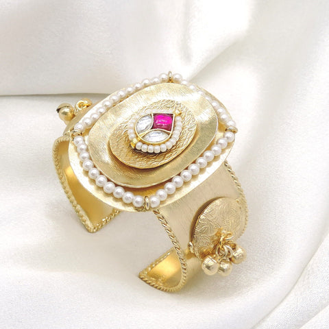 Gold-toned pink stone pearl cuff bracelet with ornate engraved detailing and dangling charms by joyrias