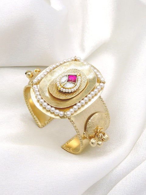 Gold-toned pink stone pearl cuff bracelet with ornate engraved detailing and dangling charms by joyrias