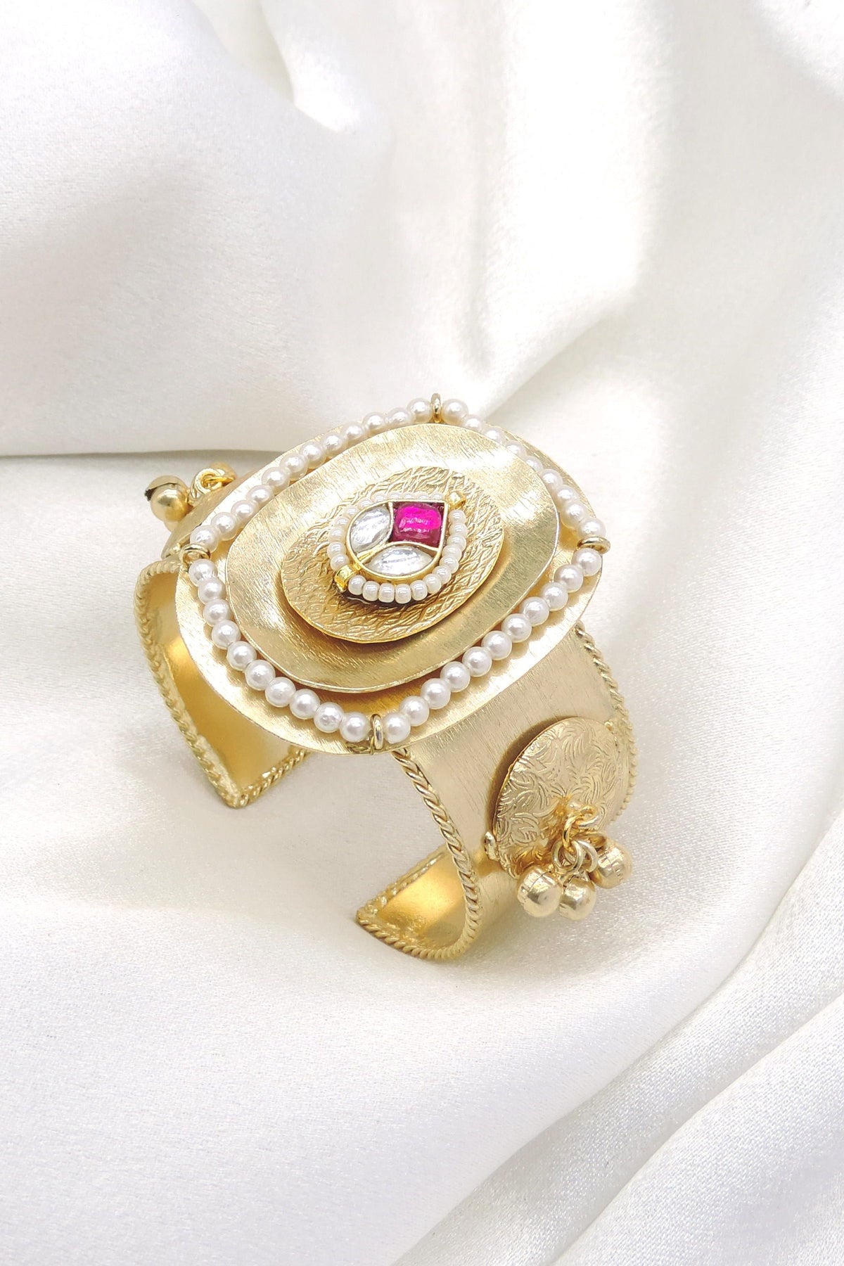 Gold-toned pink stone pearl cuff bracelet with ornate engraved detailing and dangling charms by joyrias