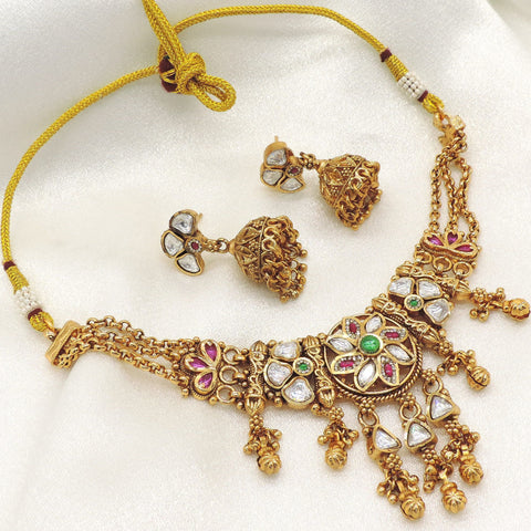 Antique gold-tone kundan choker necklace set with matching jhumka earrings featuring ruby and emerald-inspired accents, ideal for bridal wear, weddings, and festive occasions.