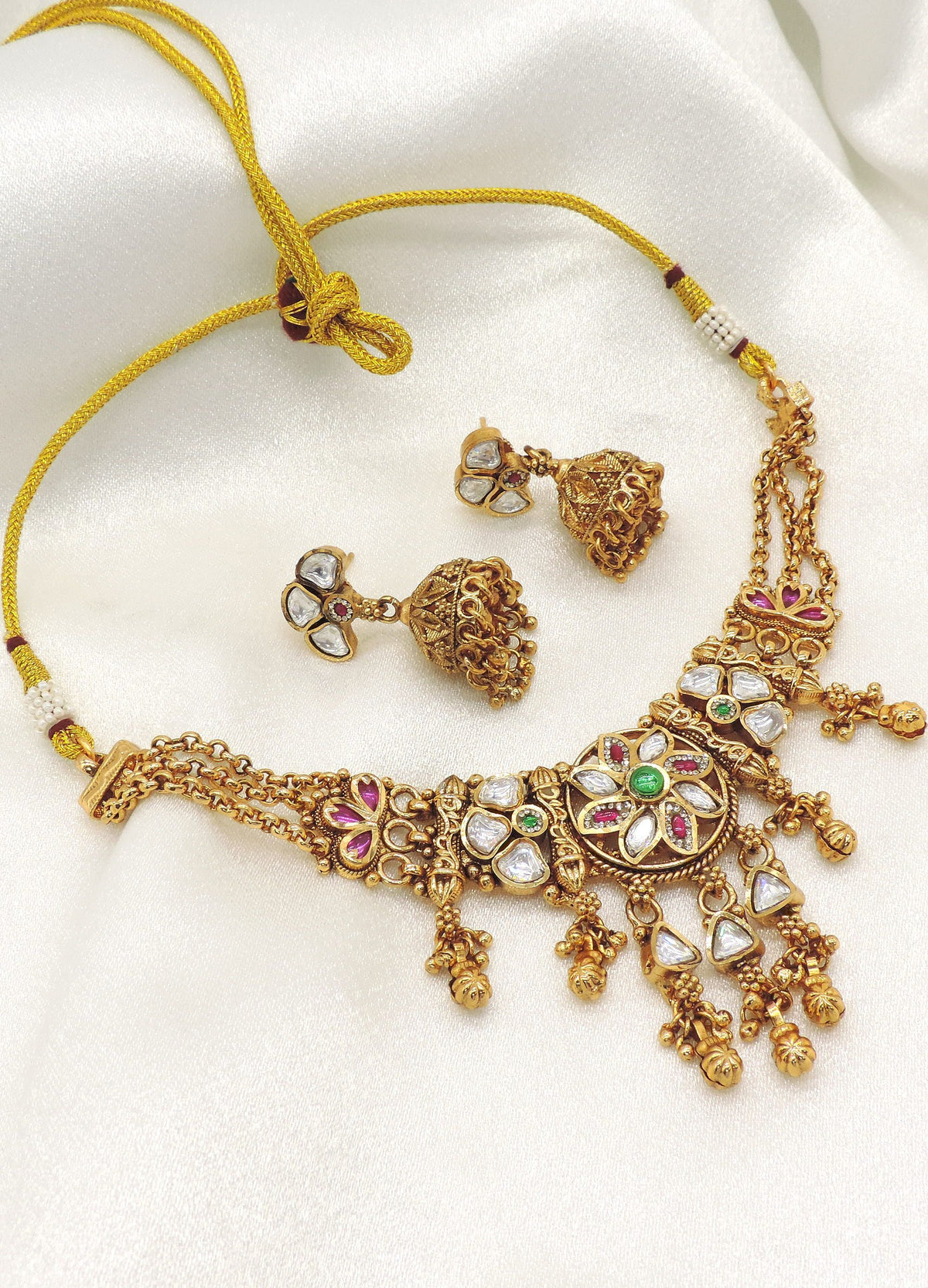 Antique gold-tone kundan choker necklace set with matching jhumka earrings featuring ruby and emerald-inspired accents, ideal for bridal wear, weddings, and festive occasions.