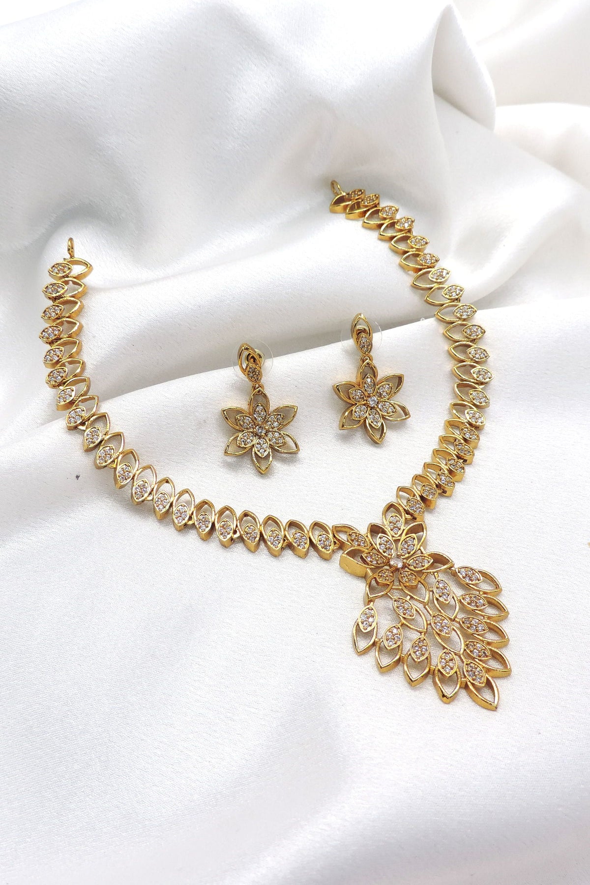 Gold tone floral CZ AD necklace set with leaf-inspired pendant and matching earrings by joyrias