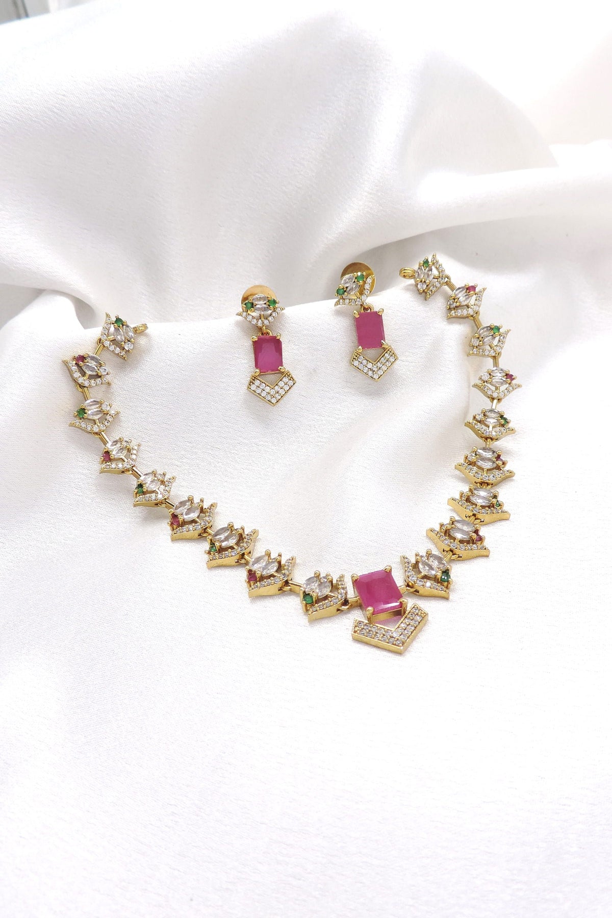 Gold-toned pink AD CZ necklace set with geometric motifs and matching earrings by joyrias