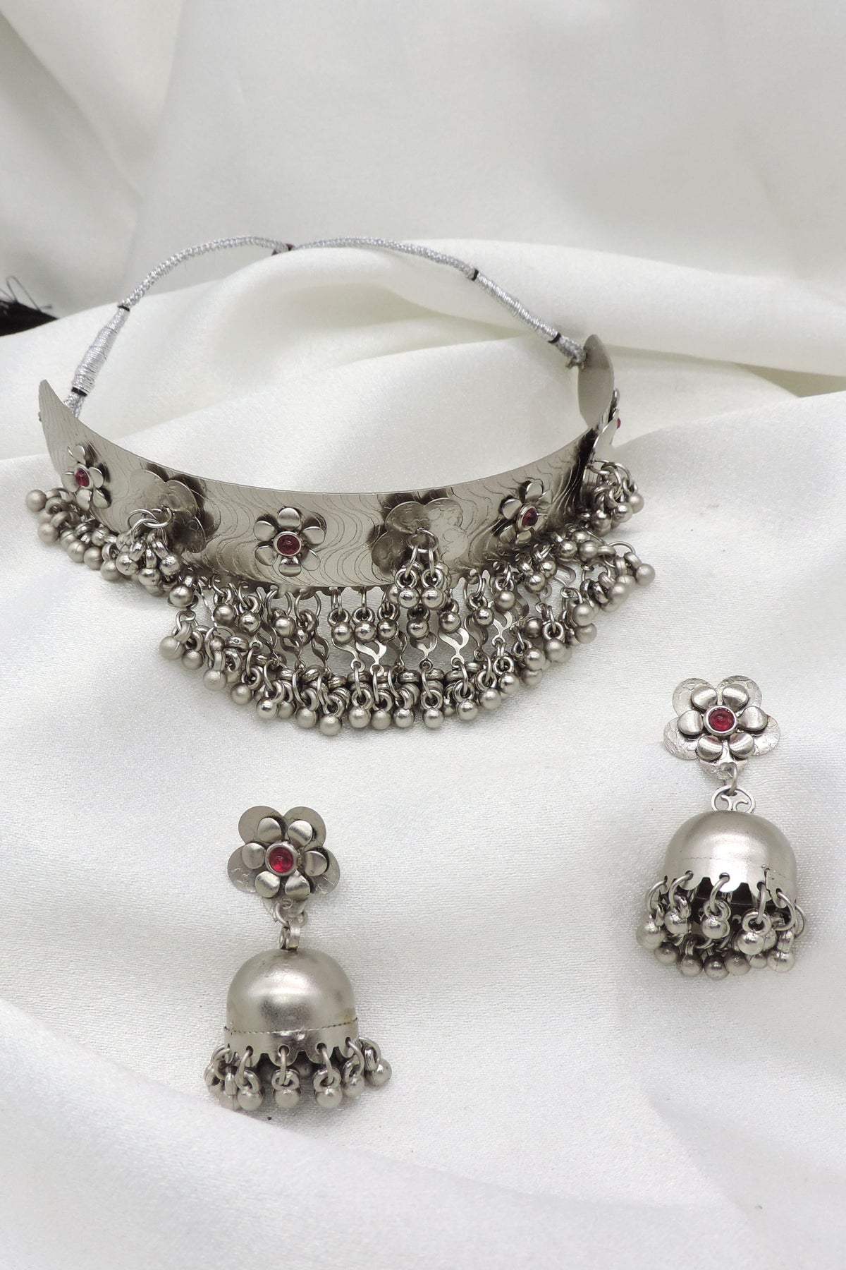 Oxidized silver floral ghungroo choker set with maroon stone accents and matching jhumka earrings by joyrias