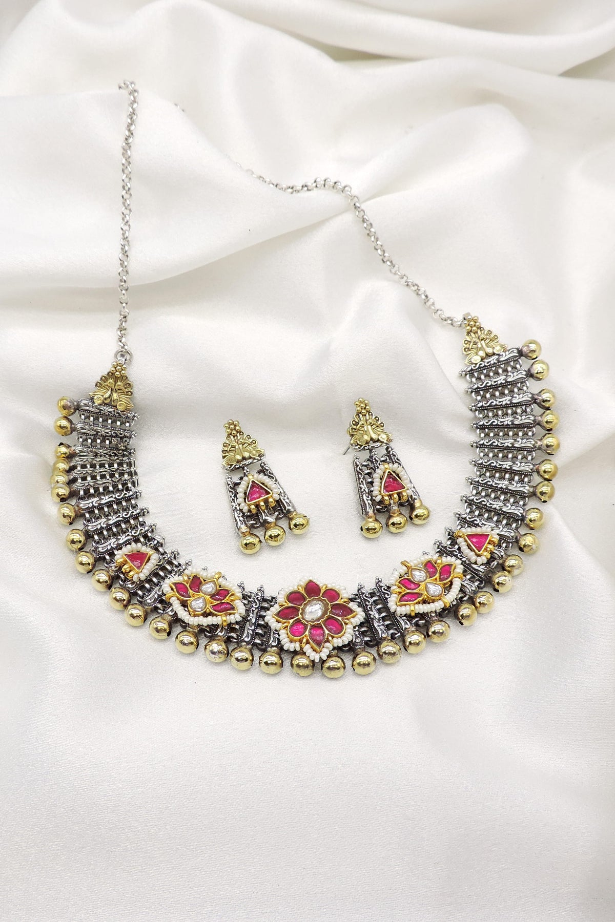 Oxidized dual-tone floral necklace set with pink stone accents, pearl detailing, and matching earrings by joyrias