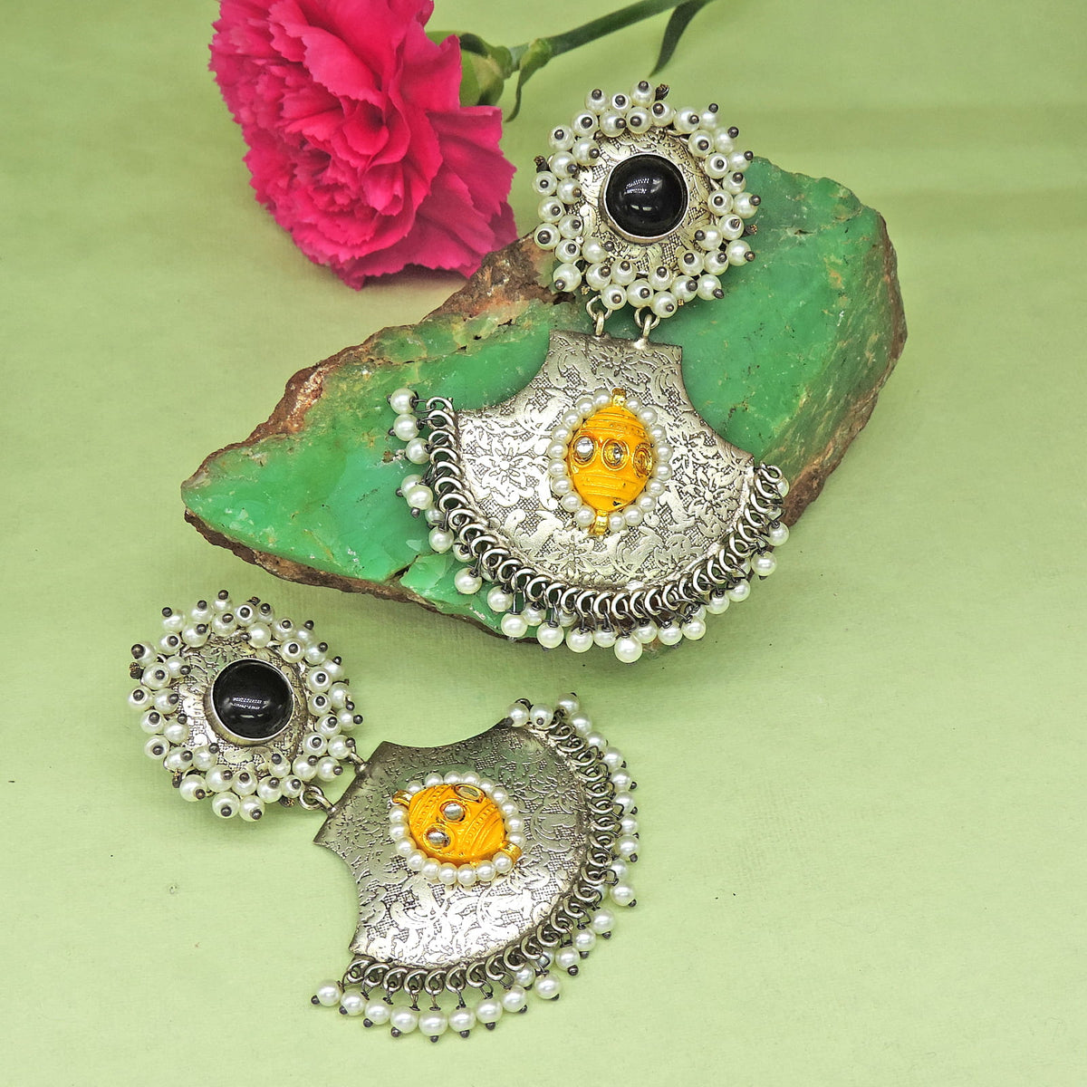 Silver jewelry set with yellow and black stones on a green stone 