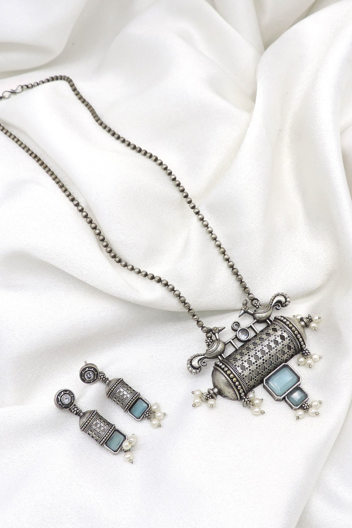 Oxidized peacock carved pendant necklace set with pearl detailing and matching earrings by joyrias