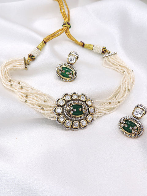 Multi-strand pearl kundan choker necklace set with green detailing, matching earrings and maang tikka by joyrias