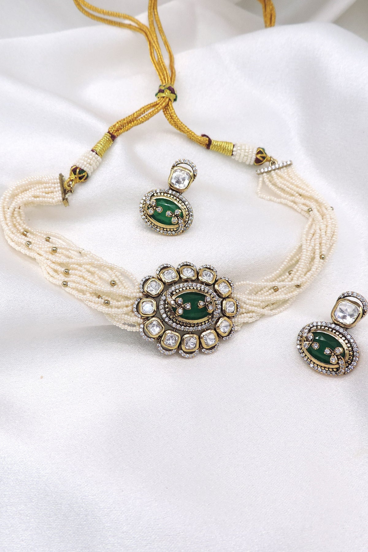 Multi-strand pearl kundan choker necklace set with green detailing, matching earrings and maang tikka by joyrias