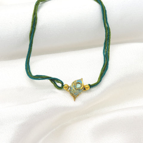 Peacock feather bhaiya rakhi with teal blue enamel and gold detailing by Joyrias