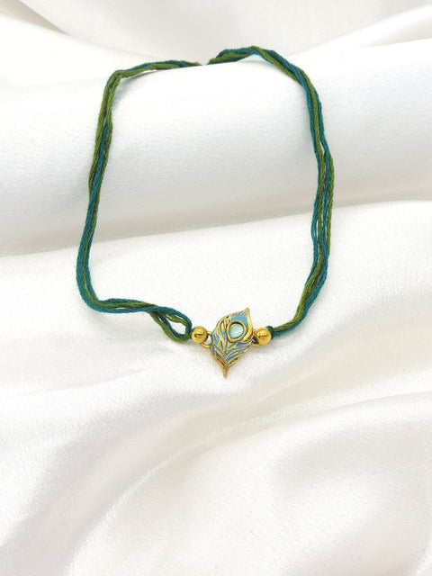 Peacock feather bhaiya rakhi with teal blue enamel and gold detailing by Joyrias