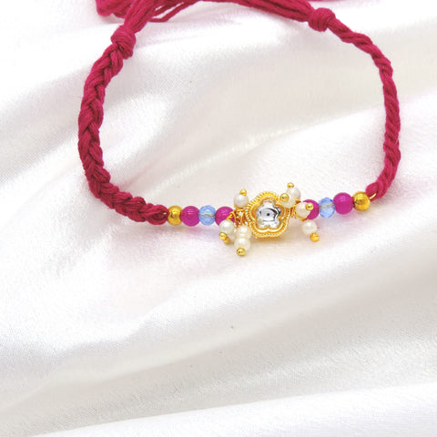 Gold floral pearl cluster bhaiya rakhi with kundan accent and pink blue beads on magenta thread by Joyrias