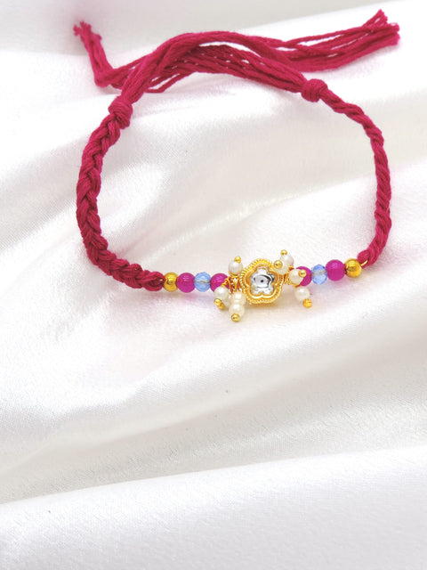 Gold floral pearl cluster bhaiya rakhi with kundan accent and pink blue beads on magenta thread by Joyrias