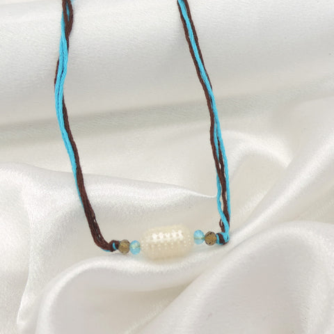 Pearl bead minimal bhaiya rakhi with turquoise and smoky brown beads on dual toned thread by Joyrias