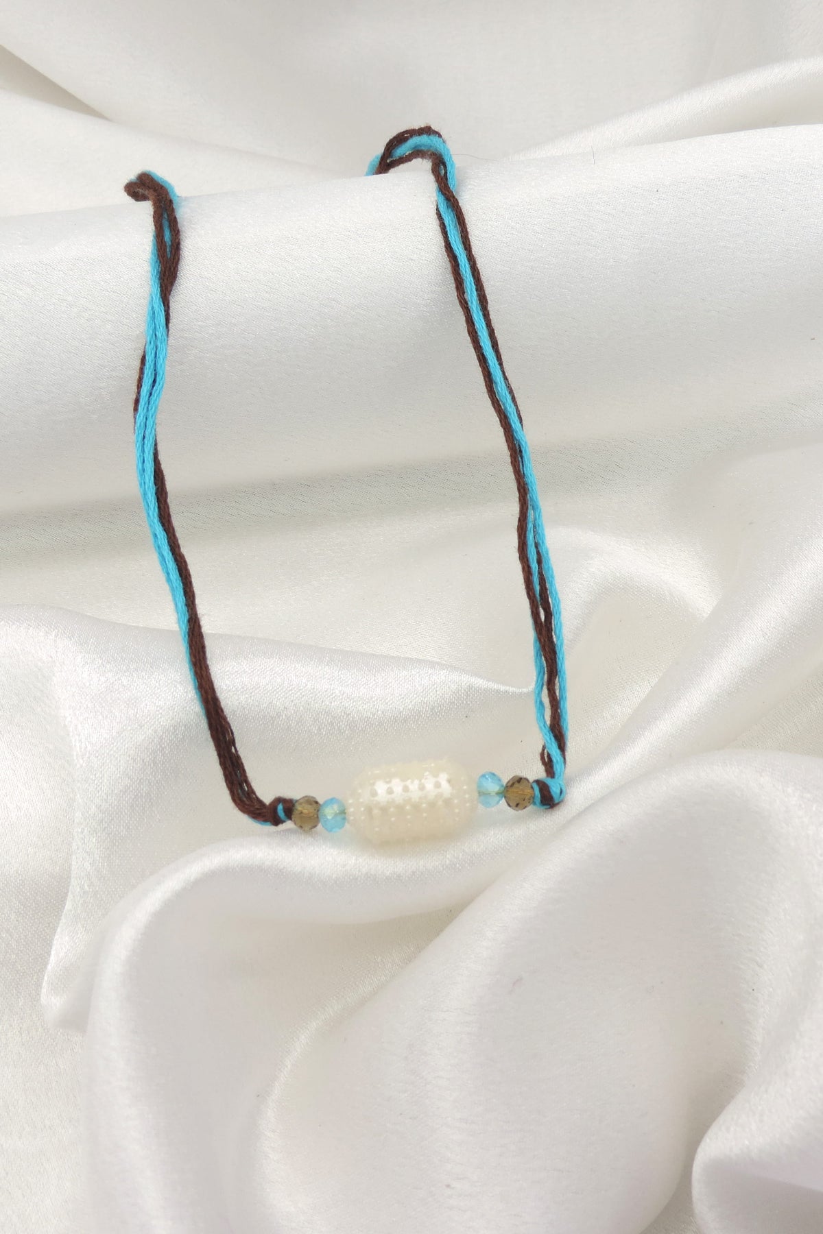 Pearl bead minimal bhaiya rakhi with turquoise and smoky brown beads on dual toned thread by Joyrias