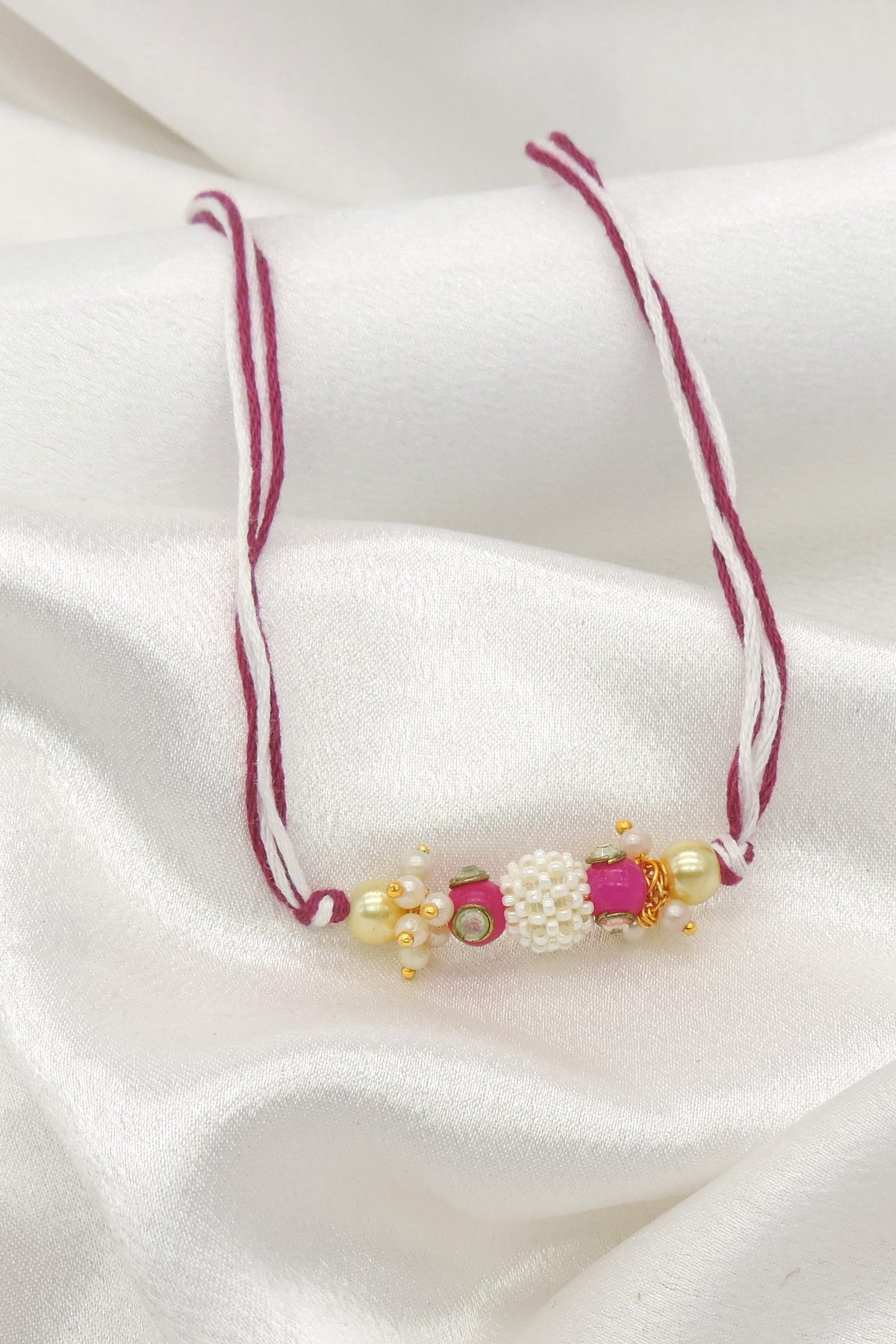 Pearl cluster bhaiya rakhi with kundan accent and pink stone on magenta white thread by Joyrias