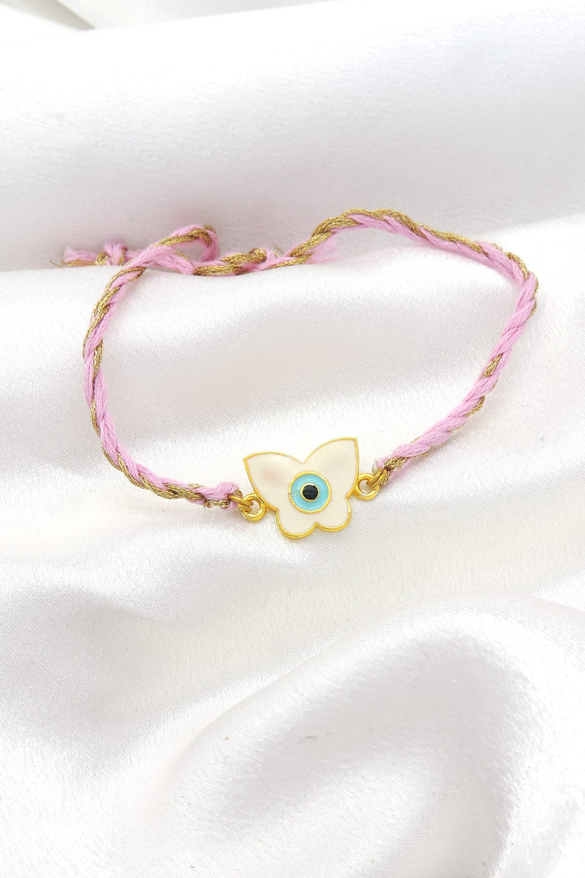 Butterfly evil eye bhaiya rakhi with white enamel charm on braided pink gold thread by Joyrias