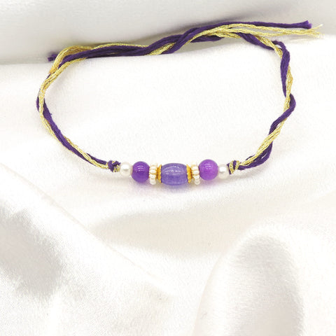 Purple bead bhaiya rakhi with lavender oval centerpiece and gold spacers on purple gold thread by Joyrias