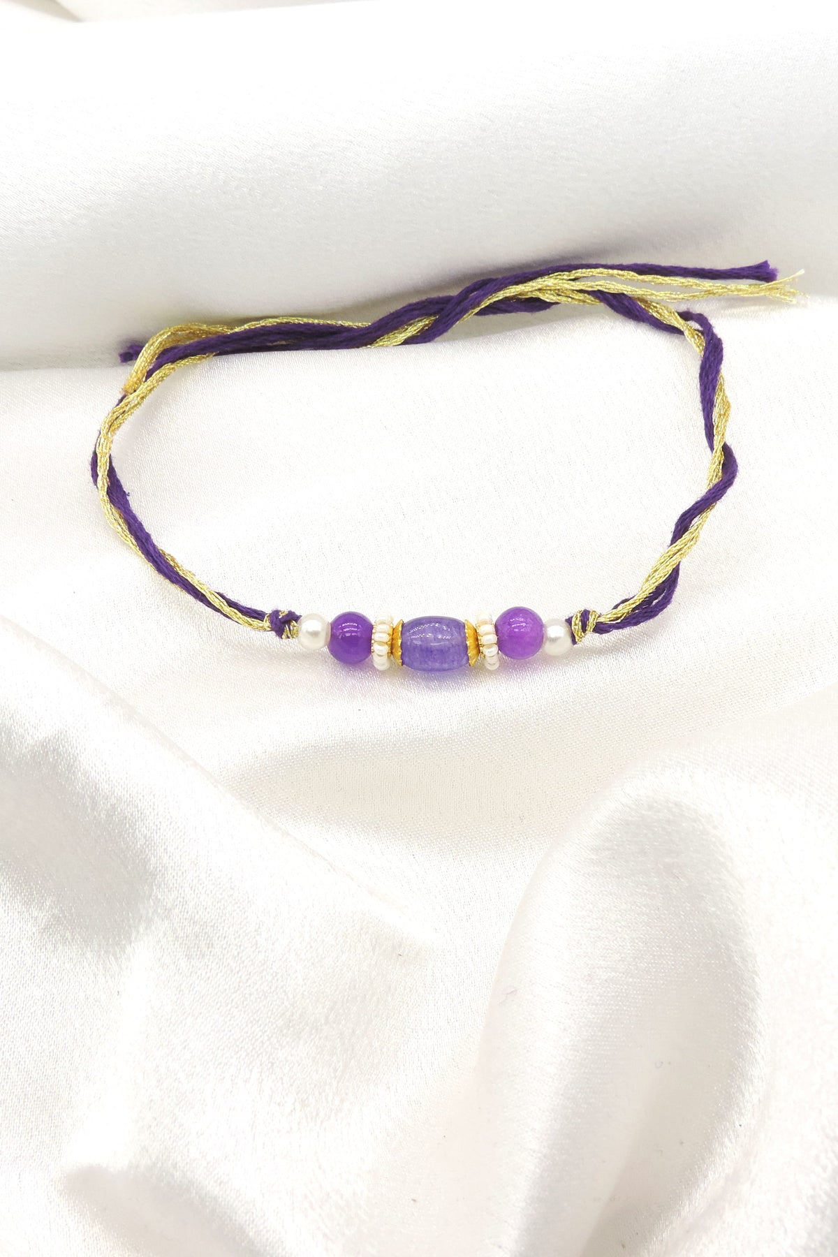 Purple bead bhaiya rakhi with lavender oval centerpiece and gold spacers on purple gold thread by Joyrias