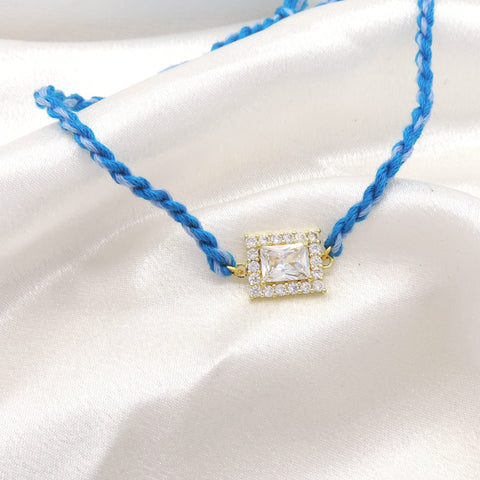 CZ square solitaire bhaiya rakhi with CZ halo border on braided blue thread by Joyrias
