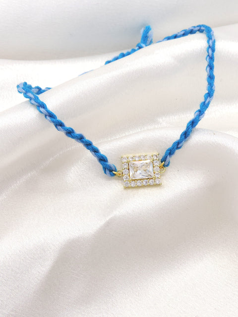 CZ square solitaire bhaiya rakhi with CZ halo border on braided blue thread by Joyrias