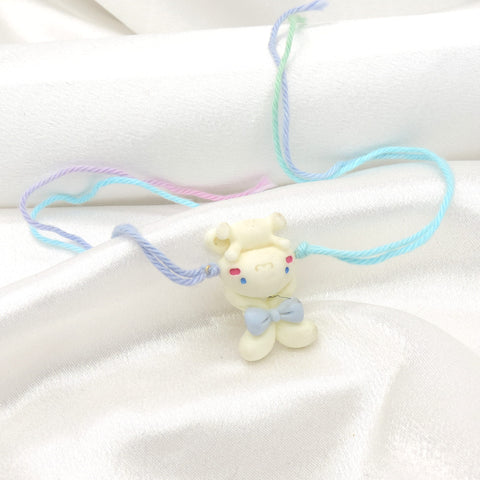 Teddy bear kids rakhi with 3D white bear charm and blue bow on pastel multicolor thread by Joyrias