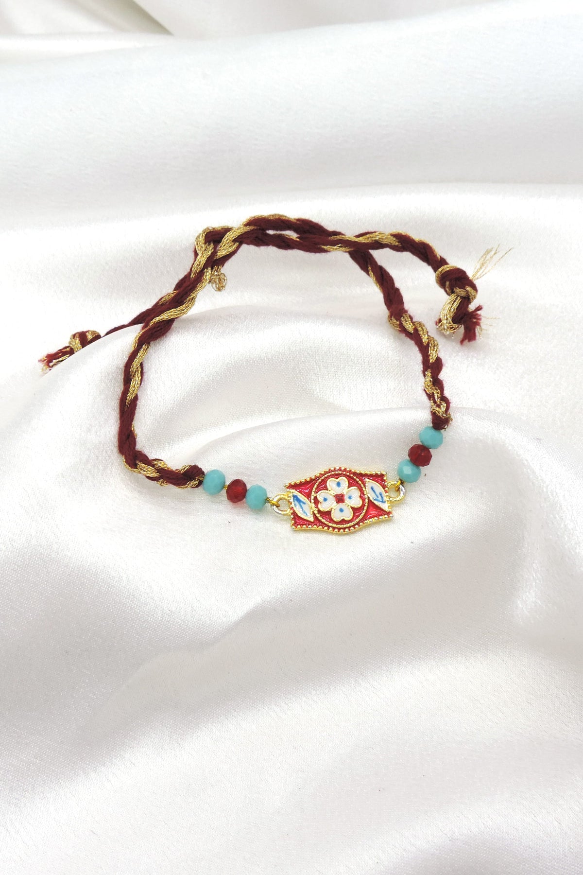 Meenakari floral rectangle bhaiya rakhi with white floral motif and turquoise beads on maroon gold thread by Joyrias