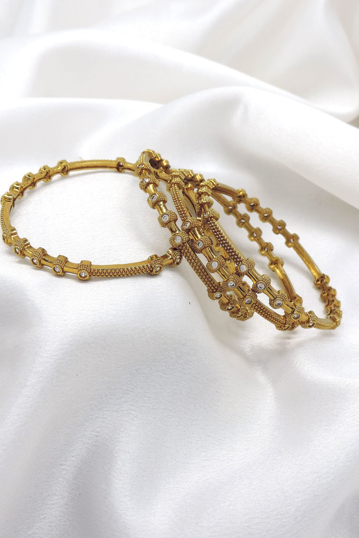 Elegant gold-toned AD detailed bangle set with intricate traditional patterns by joyrias