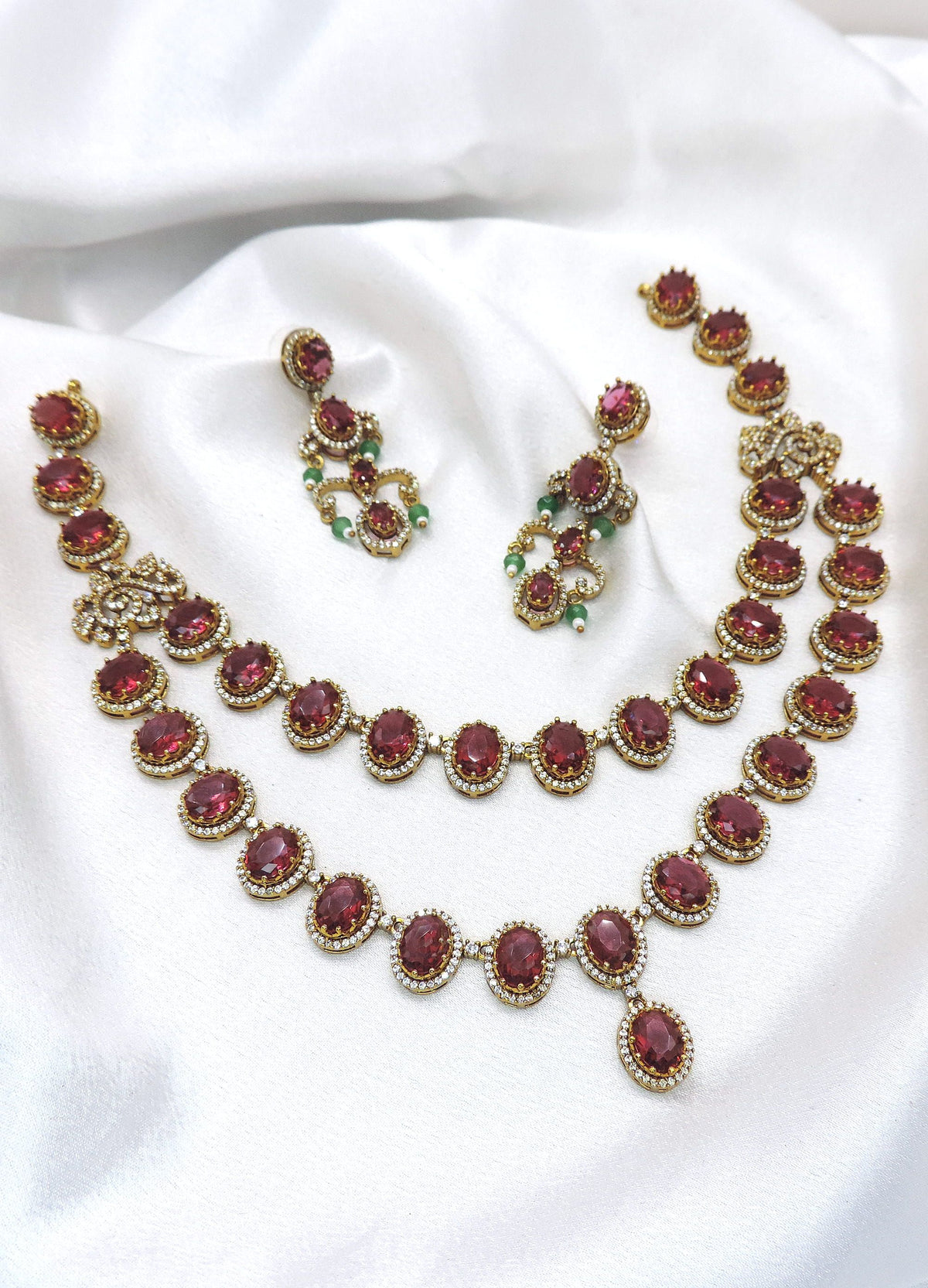Maroon kundan layered jewelry set with pearl details and matching earrings by joyrias